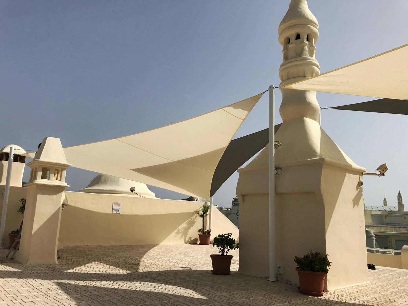 Diseño de arquitectura textil con velas de sombra rectangulares para control de temperatura exterior.